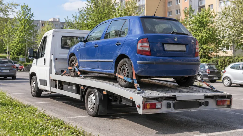 Lehký bílý odtahový vůz s upevněným automobilem Škoda