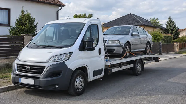 Bílý odtahový vůz s upevněným vozidlem Škoda na hliníkové plošině