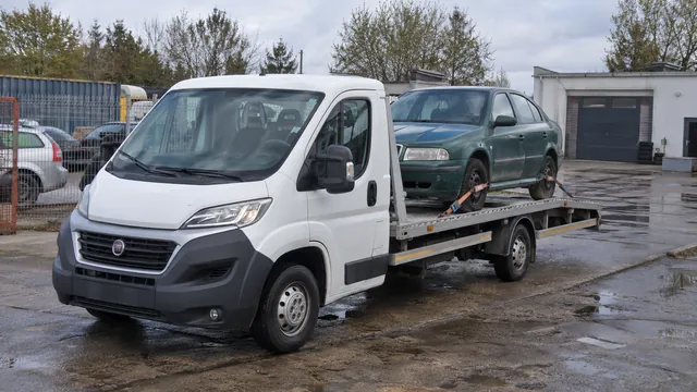 Bílý odtahový vůz s upevněným vozidlem Škoda na hliníkové plošině