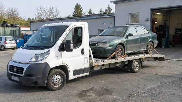 Bílý odtahový vůz s upevněným vozidlem Škoda na hliníkové plošině
