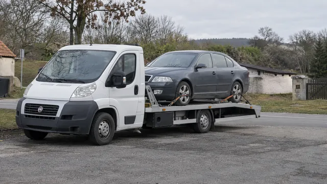 Bílý odtahový vůz s upevněným vozidlem Škoda na hliníkové plošině