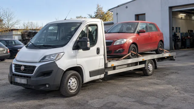 Bílý odtahový vůz s upevněným vozidlem Škoda na hliníkové plošině