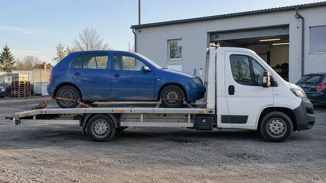 Bílý odtahový vůz s upevněným vozidlem Škoda na hliníkové plošině