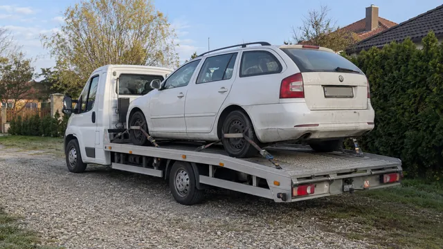 Bílý odtahový vůz s upevněným vozidlem Škoda na hliníkové plošině
