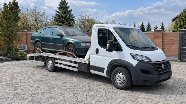 Bílý odtahový vůz s upevněným vozidlem Škoda na hliníkové plošině