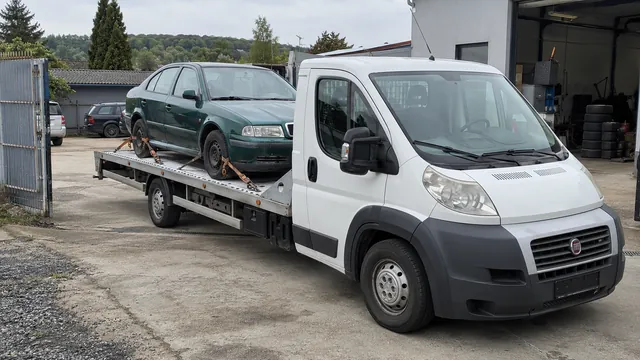 Bílý odtahový vůz s upevněným vozidlem Škoda na hliníkové plošině