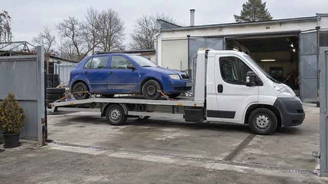 Bílý odtahový vůz s upevněným vozidlem Škoda na hliníkové plošině