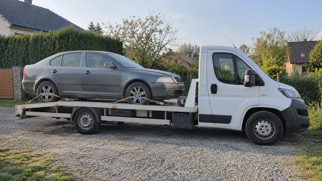 Bílý odtahový vůz s upevněným vozidlem Škoda na hliníkové plošině