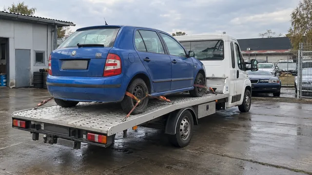 Bílý odtahový vůz s upevněným vozidlem Škoda na hliníkové plošině