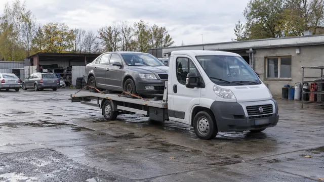 Bílý odtahový vůz s upevněným vozidlem Škoda na hliníkové plošině