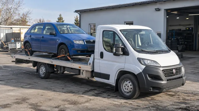 Bílý odtahový vůz s upevněným vozidlem Škoda na hliníkové plošině
