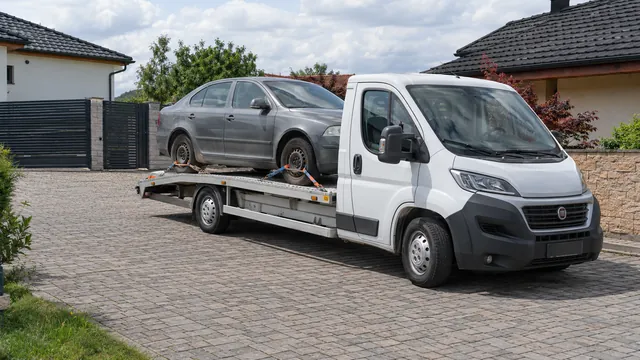 Bílý odtahový vůz s upevněným vozidlem Škoda na hliníkové plošině