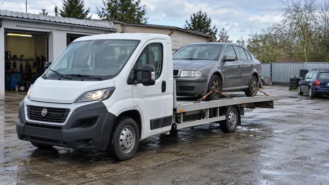 Bílý odtahový vůz s upevněným vozidlem Škoda na hliníkové plošině