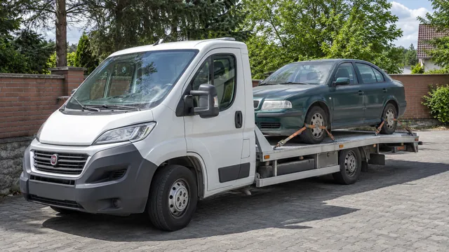 Bílý odtahový vůz s upevněným vozidlem Škoda na hliníkové plošině