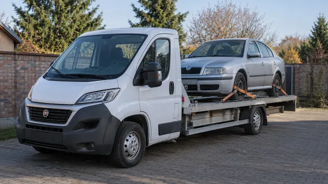 Bílý odtahový vůz s upevněným vozidlem Škoda na hliníkové plošině