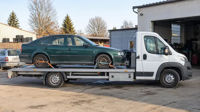 Bílý odtahový vůz s upevněným vozidlem Škoda na hliníkové plošině