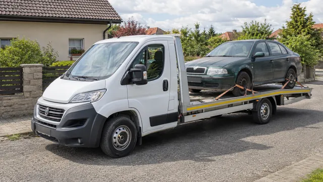 Bílý odtahový vůz s upevněným vozidlem Škoda na hliníkové plošině