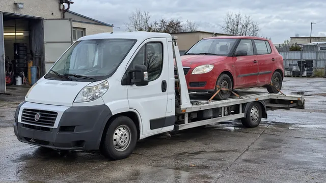 Bílý odtahový vůz s upevněným vozidlem Škoda na hliníkové plošině