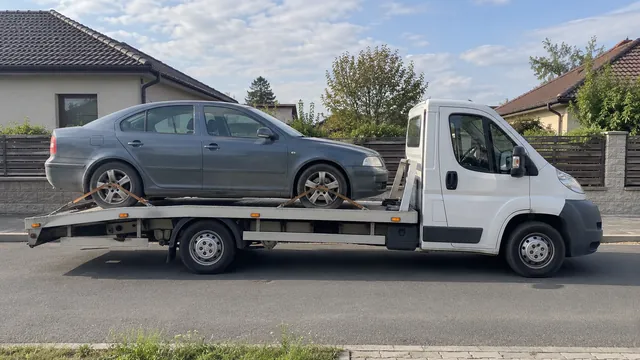Bílý odtahový vůz s upevněným vozidlem Škoda na hliníkové plošině