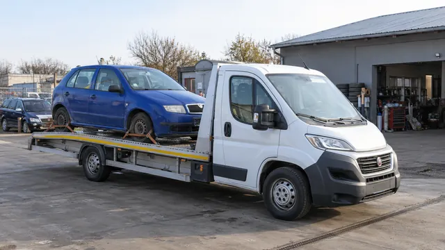 Bílý odtahový vůz s upevněným vozidlem Škoda na hliníkové plošině