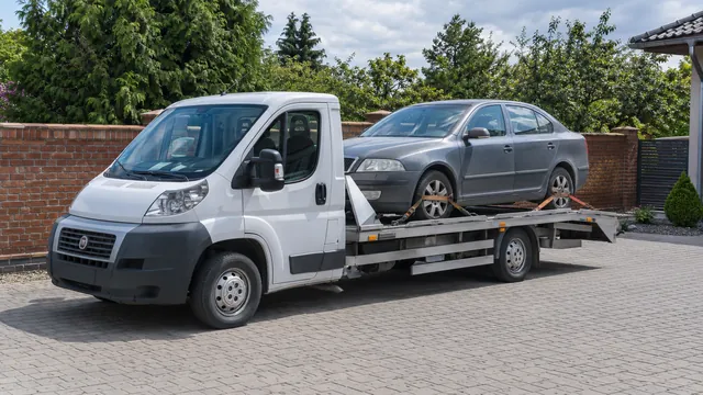 Bílý odtahový vůz s upevněným vozidlem Škoda na hliníkové plošině