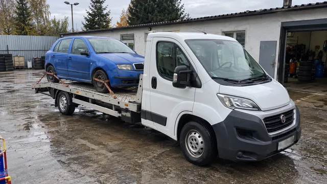 Bílý odtahový vůz s upevněným vozidlem Škoda na hliníkové plošině
