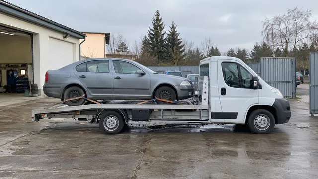 Bílý odtahový vůz s upevněným vozidlem Škoda na hliníkové plošině