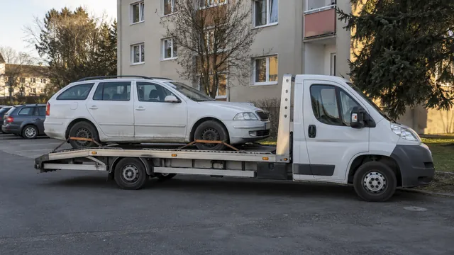 Bílý odtahový vůz s upevněným vozidlem Škoda na hliníkové plošině