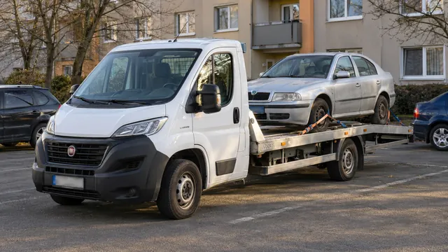 Bílý odtahový vůz s upevněným vozidlem Škoda na hliníkové plošině