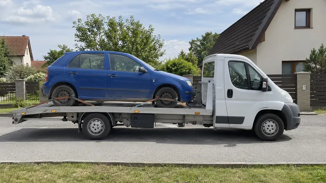 Bílý odtahový vůz s upevněným vozidlem Škoda na hliníkové plošině