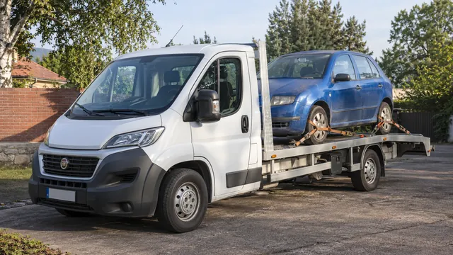 Bílý odtahový vůz s upevněným vozidlem Škoda na hliníkové plošině