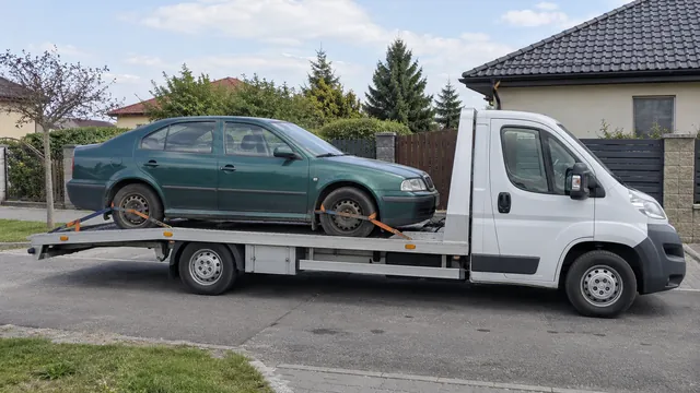 Bílý odtahový vůz s upevněným vozidlem Škoda na hliníkové plošině