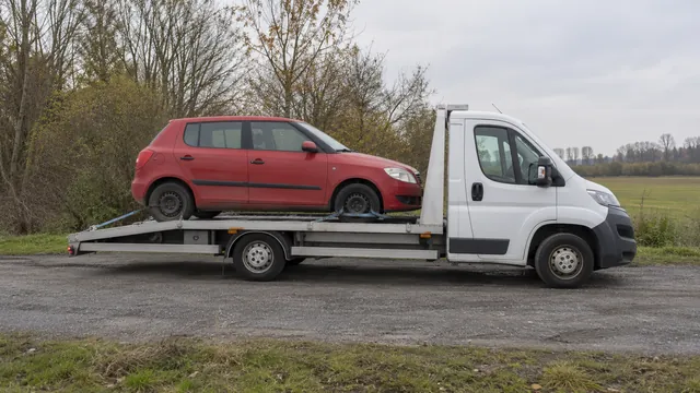 Bílý odtahový vůz s upevněným vozidlem Škoda na hliníkové plošině