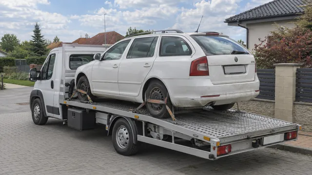 Bílý odtahový vůz s upevněným vozidlem Škoda na hliníkové plošině