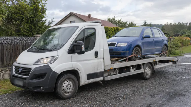 Bílý odtahový vůz s upevněným vozidlem Škoda na hliníkové plošině