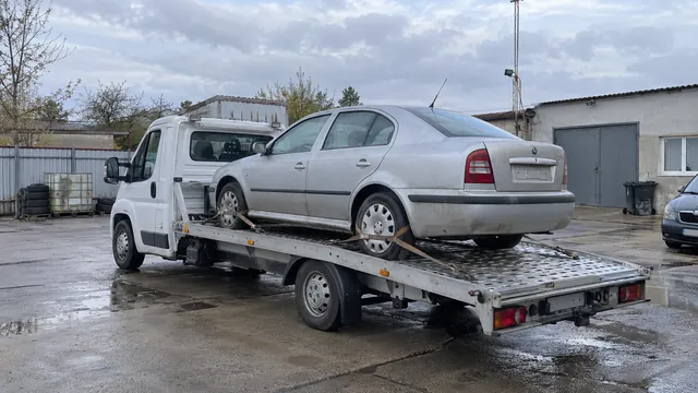 Bílý odtahový vůz s upevněným vozidlem Škoda na hliníkové plošině