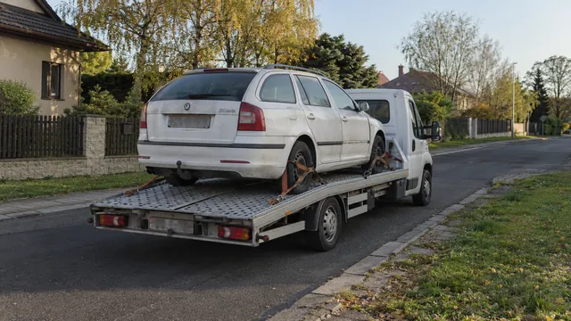 Bílý odtahový vůz s upevněným vozidlem Škoda na hliníkové plošině