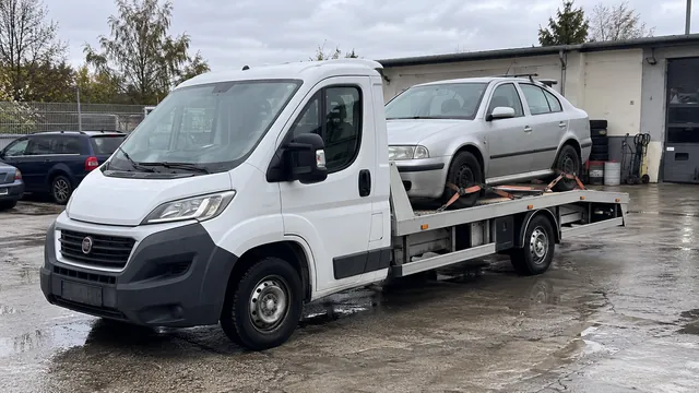 Bílý odtahový vůz s upevněným vozidlem Škoda na hliníkové plošině