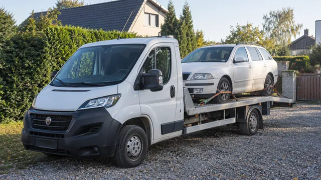 Bílý odtahový vůz s upevněným vozidlem Škoda na hliníkové plošině