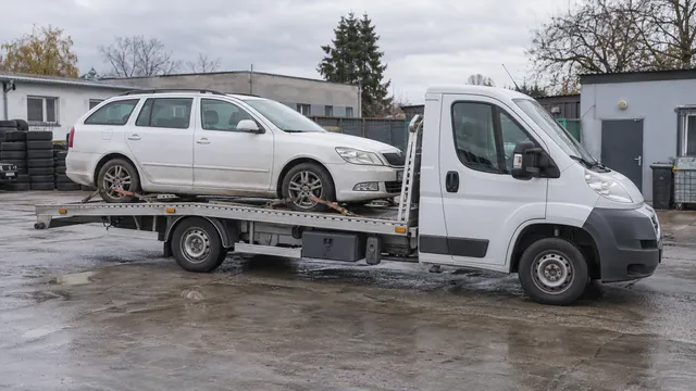 Bílý odtahový vůz s upevněným vozidlem Škoda na hliníkové plošině