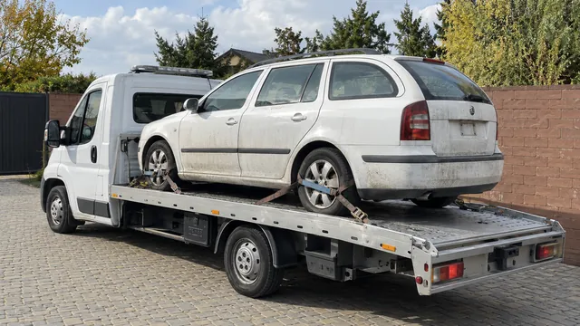 Bílý odtahový vůz s upevněným vozidlem Škoda na hliníkové plošině
