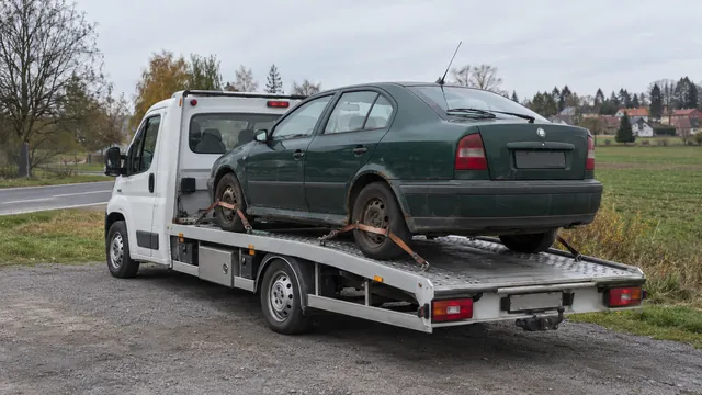 Bílý odtahový vůz s upevněným vozidlem Škoda na hliníkové plošině