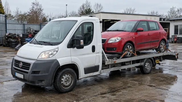 Bílý odtahový vůz s upevněným vozidlem Škoda na hliníkové plošině