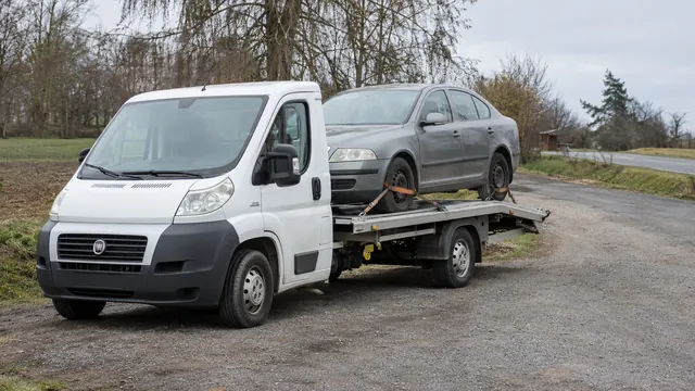 Bílý odtahový vůz s upevněným vozidlem Škoda na hliníkové plošině