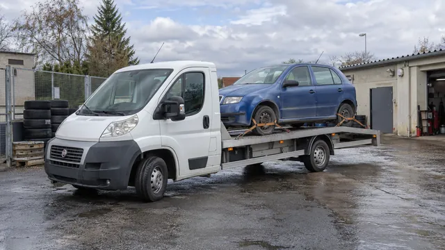 Bílý odtahový vůz s upevněným vozidlem Škoda na hliníkové plošině