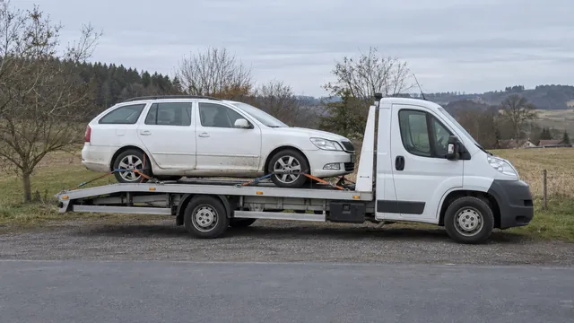 Bílý odtahový vůz s upevněným vozidlem Škoda na hliníkové plošině