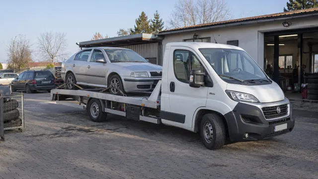Bílý odtahový vůz s upevněným vozidlem Škoda na hliníkové plošině