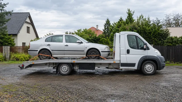 Bílý odtahový vůz s upevněným vozidlem Škoda na hliníkové plošině