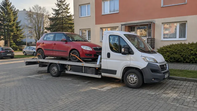Bílý odtahový vůz s upevněným vozidlem Škoda na hliníkové plošině