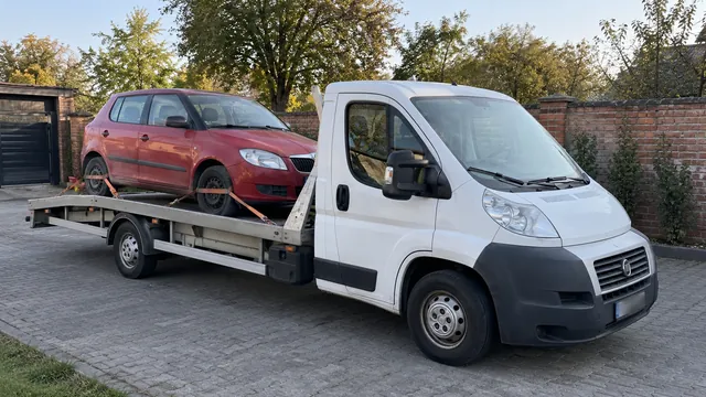 Bílý odtahový vůz s upevněným vozidlem Škoda na hliníkové plošině